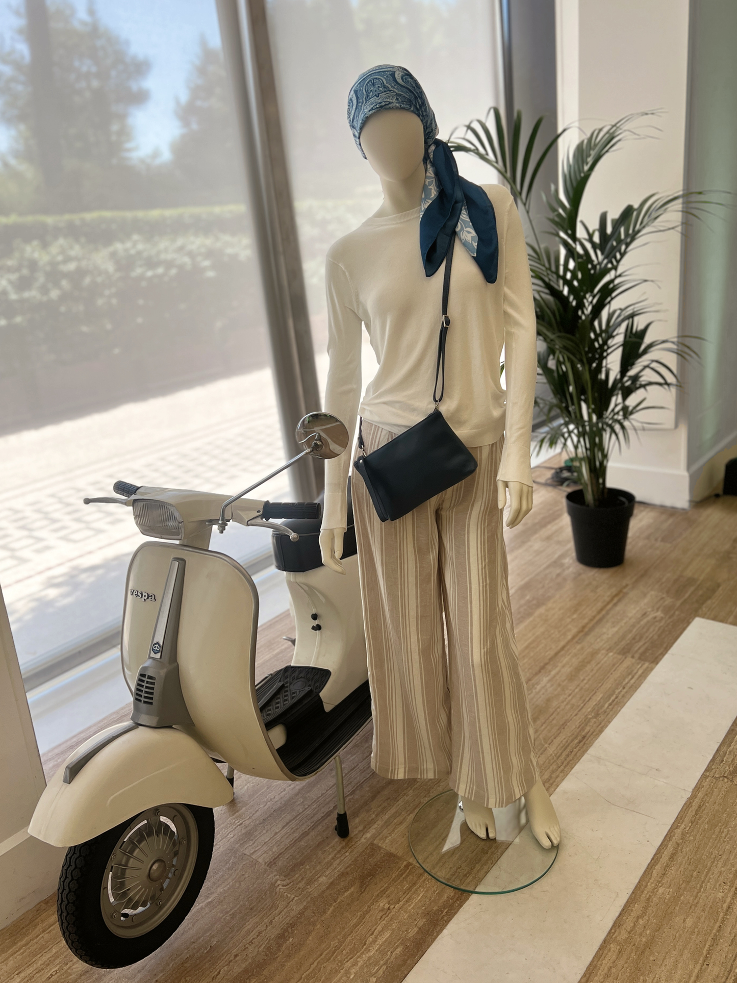 'Aria' Euro-inspired leather cross body bag with wristlet strap on mannequin with vespa - Rome, Italy